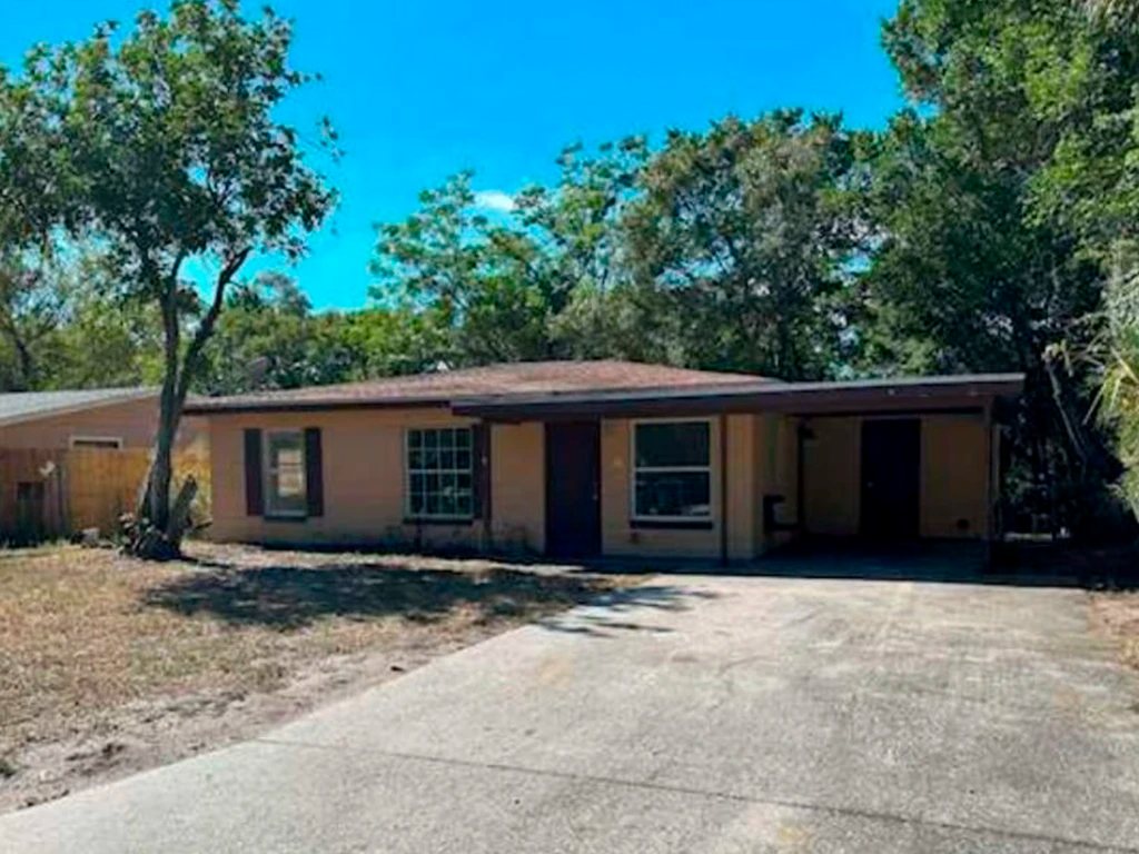 Before: faded tan block home with sagging carport